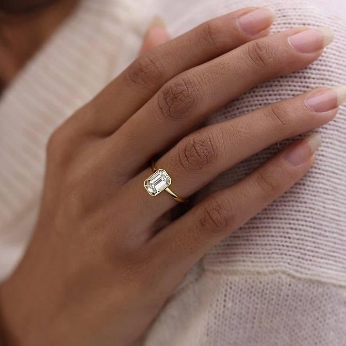 Bezel set emerald cut engagement ring in yellow gold with lab-grown diamond