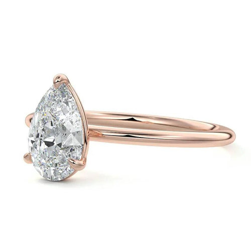 Rose gold ring with a pear-shaped diamond on a white background