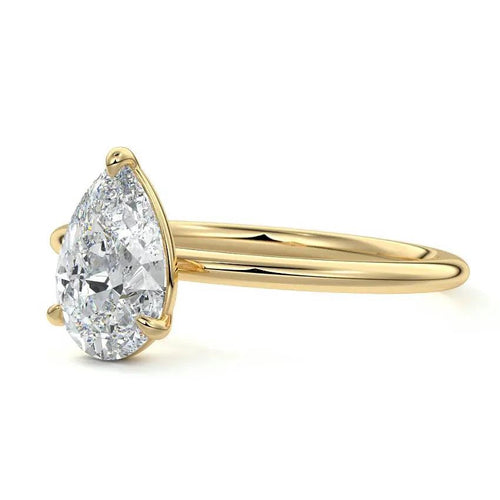 Gold ring with a pear-shaped diamond on a white background