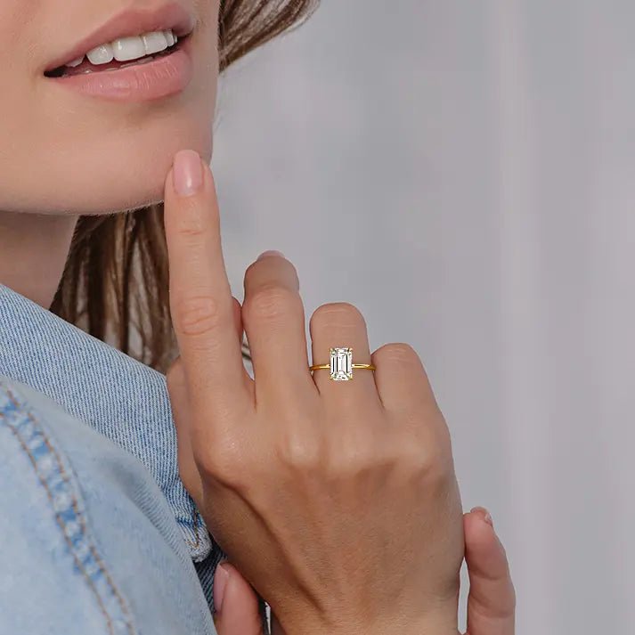Close-up of emerald cut diamond ring held between model fingers