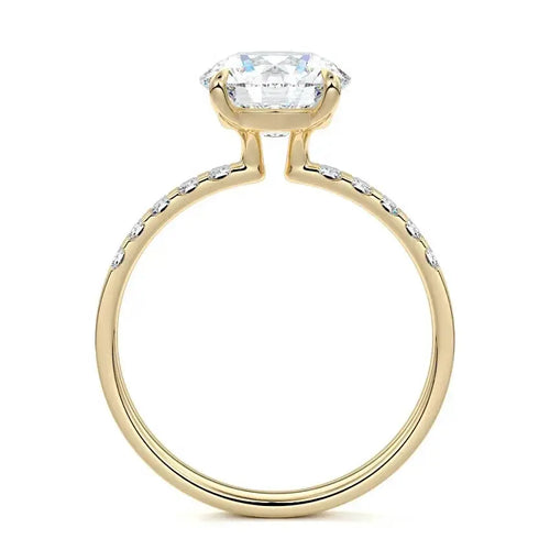 Round cut engagement ring with emerald cut side stones in 18K yellow gold by Nura Lab