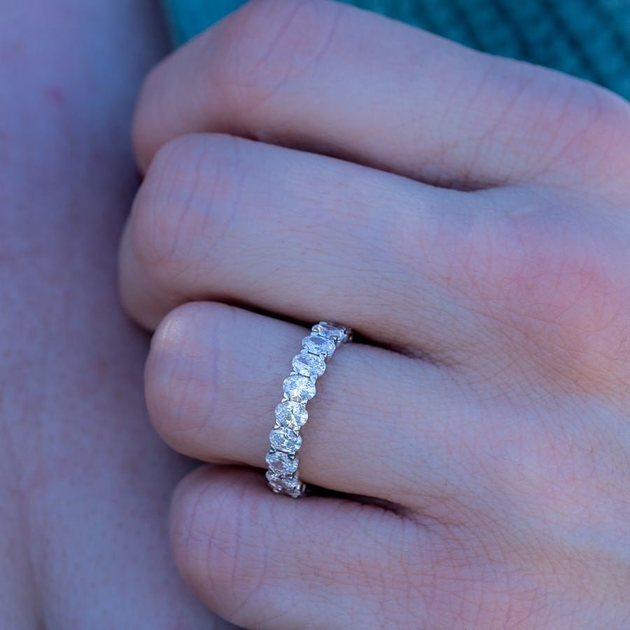 Hand model wearing 3 carat oval eternity band in 14K yellow gold